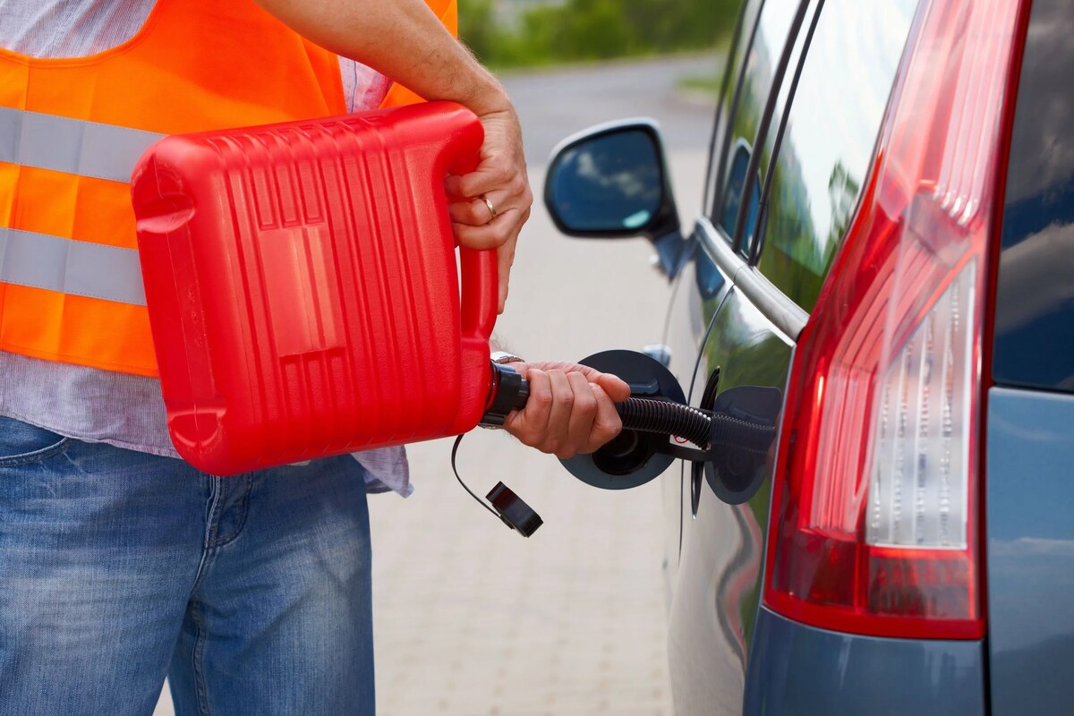Pacific Unlocks roadside fuel delivery — uniformed technician in safety vest refueling a stranded vehicle with a portable gasoline safety can in Honolulu, Oahu, Hawaii
